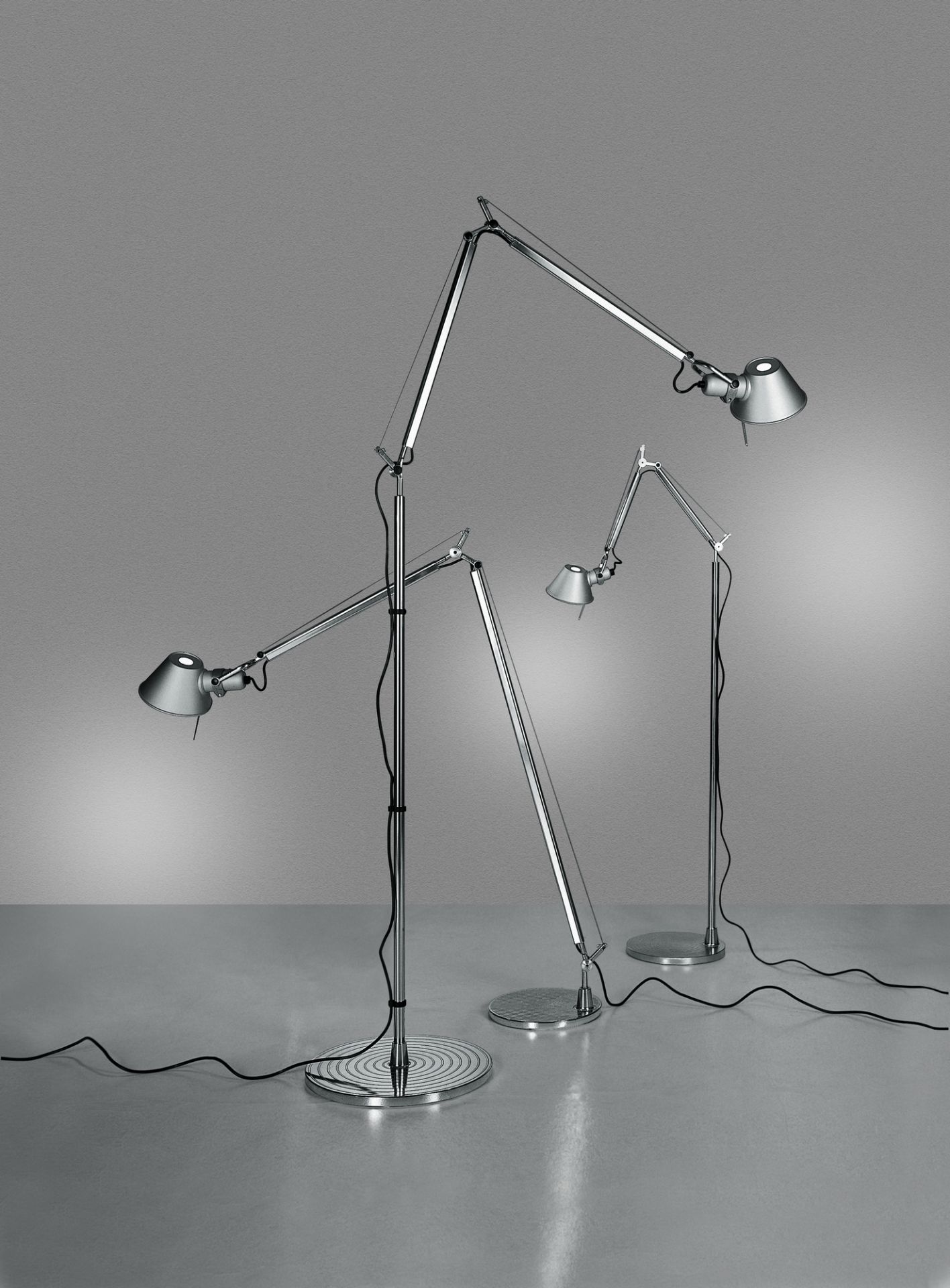 Drei moderne, silberne Tolomeo Stehleuchten von Artemide mit verstellbaren Armen und konischen Lampenschirmen.